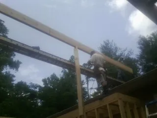 Carpenter setting a ridge beam over a new addition frame — Ice Dam Removal by Roofing Brothers in Prince George