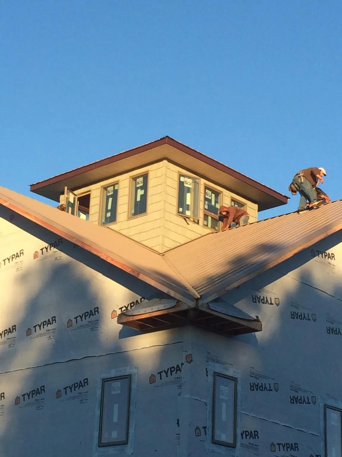 Roofers working around a rooftop cupola on a new metal roof at sunset — Roof Waterproofing in Prince George by Roofing Brothers